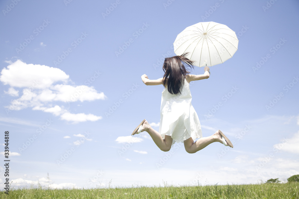 日傘を持ってジャンプする女性の後ろ姿 Stock Photo Adobe Stock