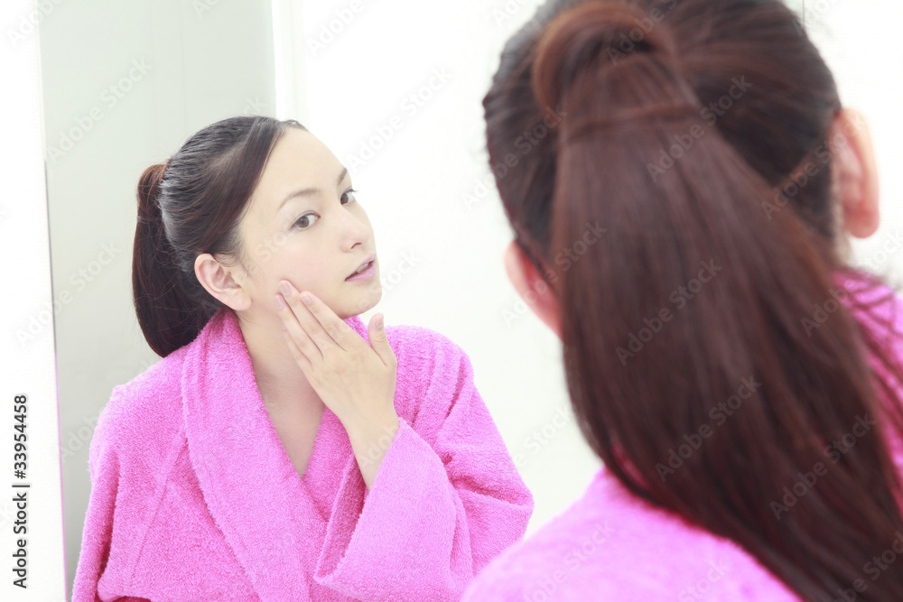 洗面台で自分の肌を気にする女性 洗面台で自分の肌を気にする女性
