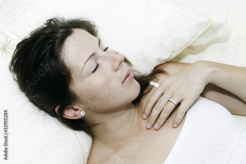 Красивая молодая женщина спит на белой постели