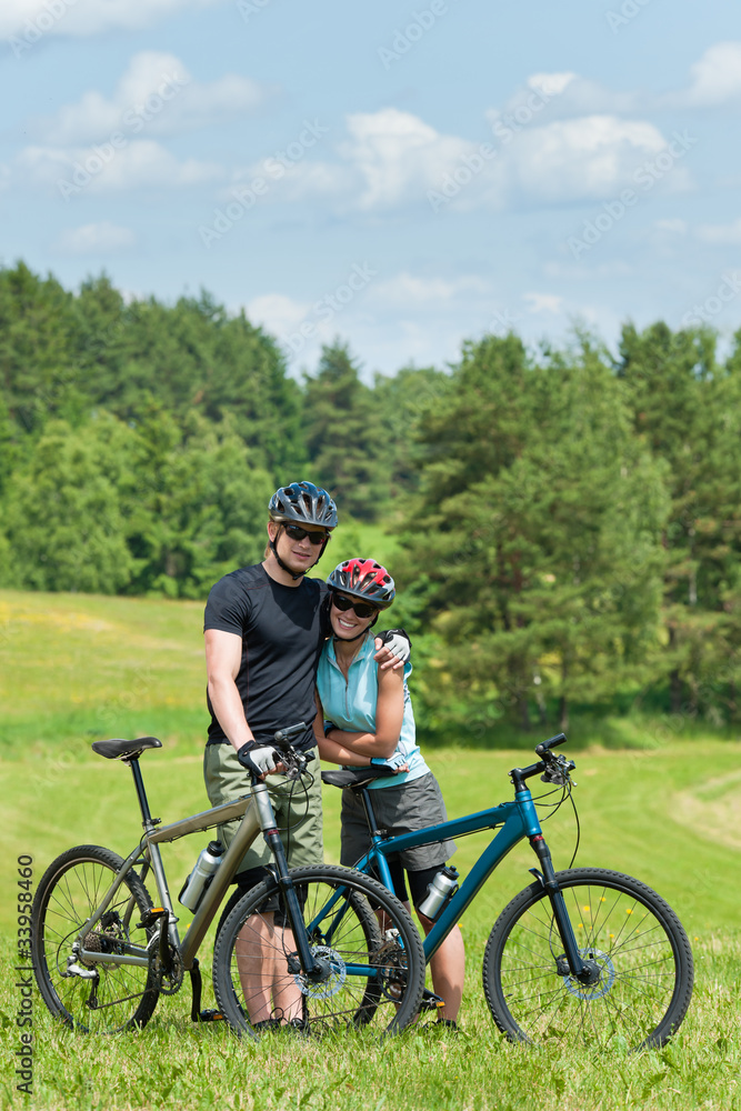 Sport mountain biking couple relax in meadows Sport mountain biking couple relax in meadows