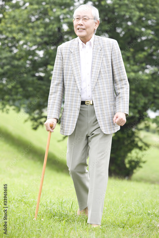 公園を杖をつきながら散歩する老人 公園を杖をつきながら散歩する老人