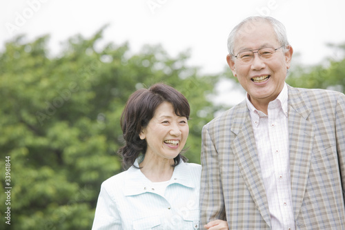 腕を組みながら公園を散歩する老夫婦