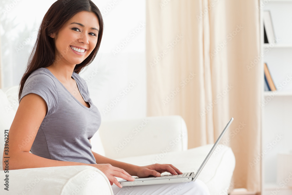 close up of a smiling woman sitting crossleged on sofa working w close up of a smiling woman sitting crossleged on sofa working w
