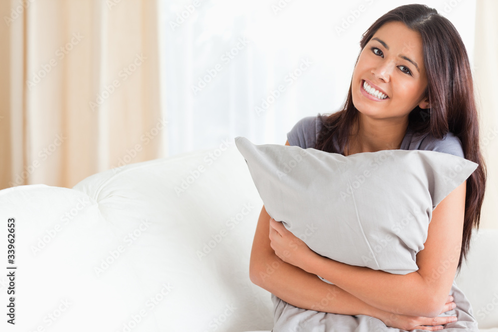 charming woman with pillow in her arms looking into camera charming woman with pillow in her arms looking into camera