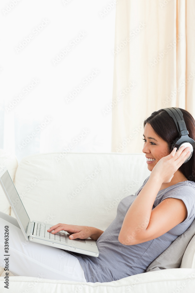 young woman with earphones on sitting on sofa young woman with earphones on sitting on sofa