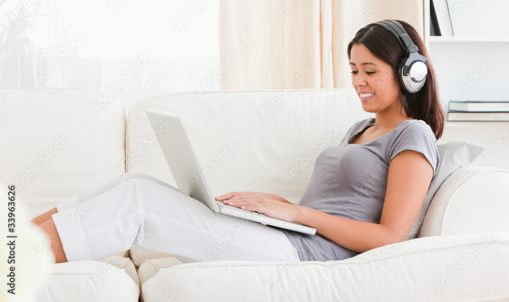 woman with notebook and earphones sitting on a sofa woman with notebook and earphones sitting on a sofa