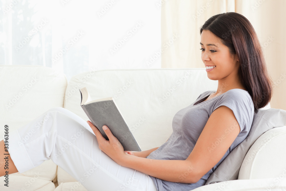 young woman reading a book sitting on sofa young woman reading a book sitting on sofa
