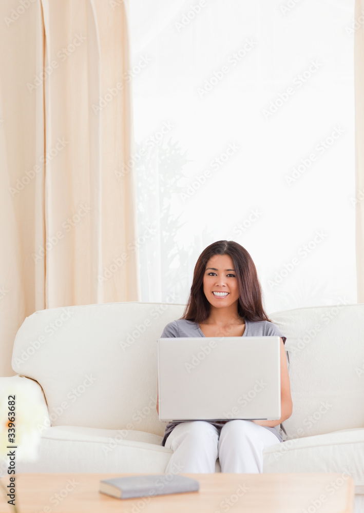 charming woman with notebook sitting on a sofa charming woman with notebook sitting on a sofa