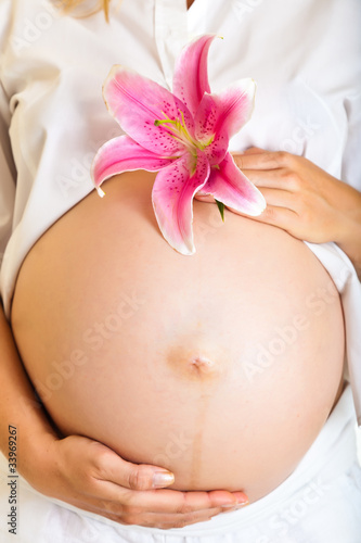 Pregnant woman holding lillies isolated on white