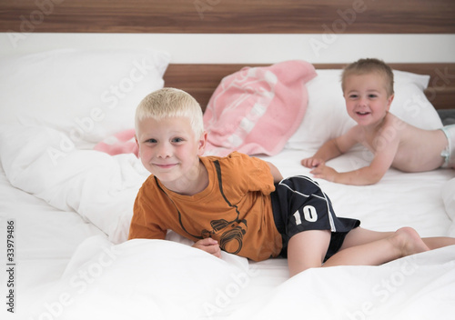 Young cheerful brothers in white bed