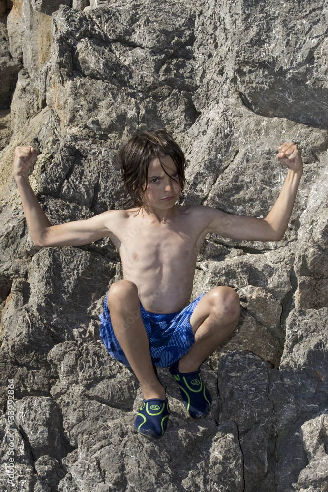Junge sitzt am Meer auf Felsen Junge sitzt am Meer auf Felsen