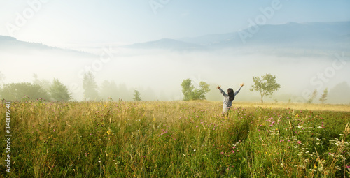 Young woman with arms raised in the misty morning