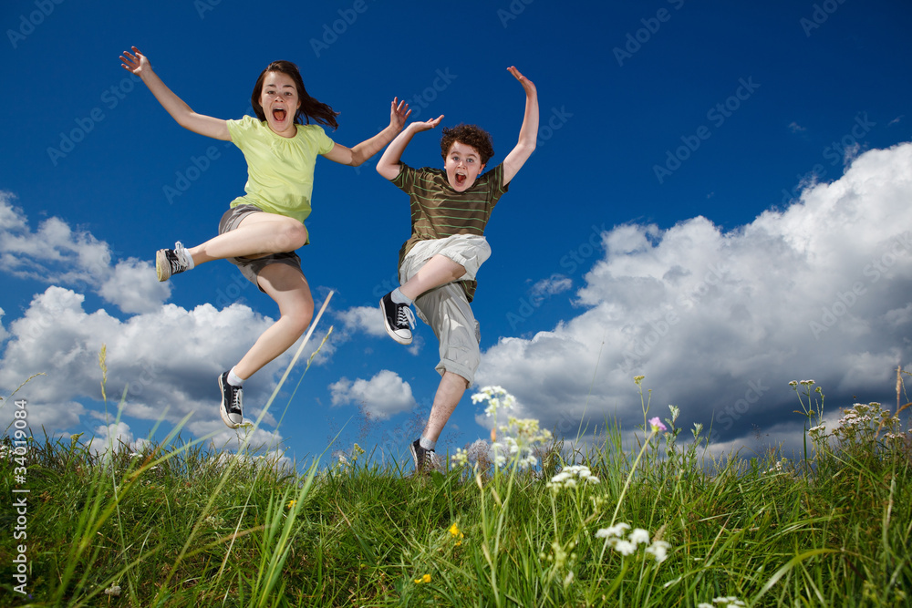Girl and boy jumping, running against blue sky Girl and boy jumping, running against blue sky