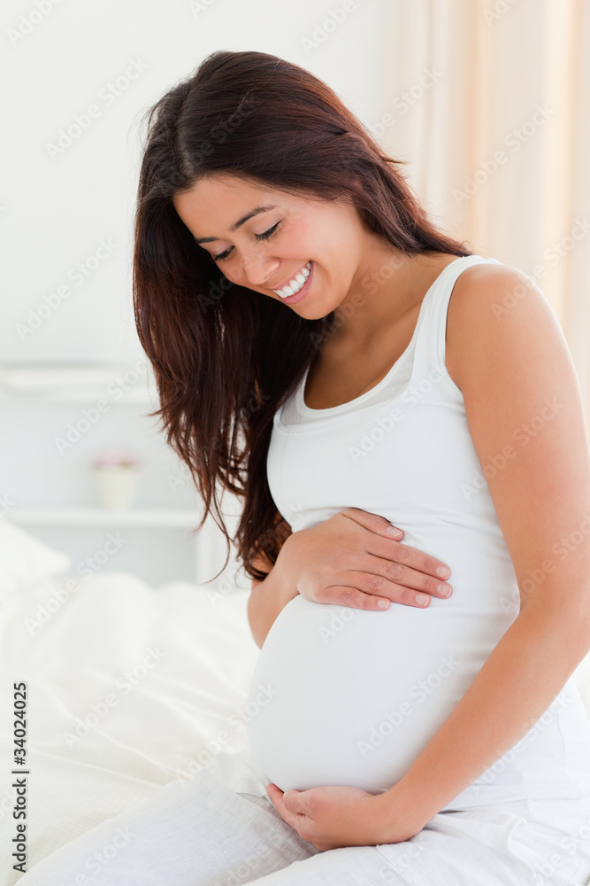 Portrait of an attractive pregnant woman touching her belly whil Portrait of an attractive pregnant woman touching her belly whil