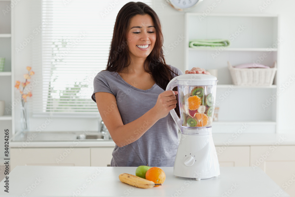 Charming woman using a blender while standing Charming woman using a blender while standing