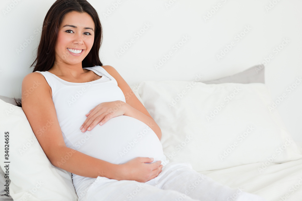 Frontal view of a beautiful pregnant woman touching her belly wh Frontal view of a beautiful pregnant woman touching her belly wh