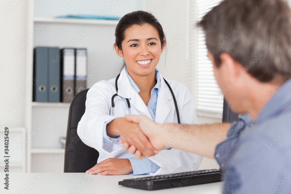 Pretty female doctor shaking a patient's hands Pretty female doctor shaking a patient's hands