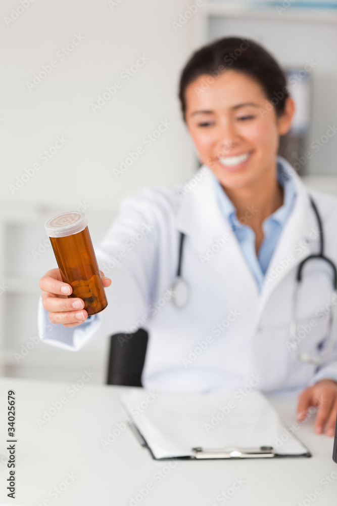 Gorgeous smiling doctor holding a box of pills while sitting Gorgeous smiling doctor holding a box of pills while sitting