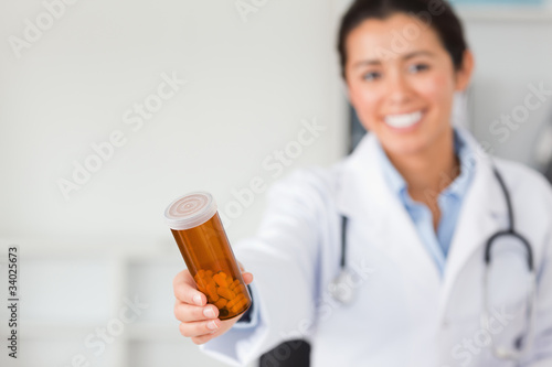 Gorgeous smiling doctor holding a box of pills