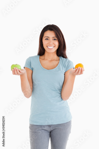 Attractive woman holding an apple and an orange