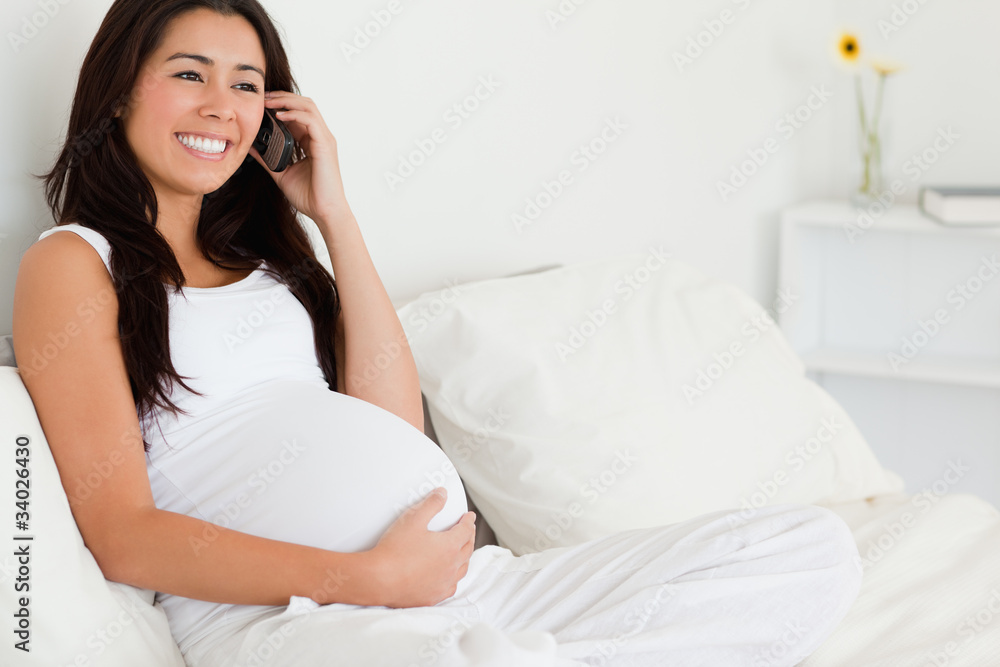 Gorgeous pregnant woman on the phone while lying on a bed Gorgeous pregnant woman on the phone while lying on a bed