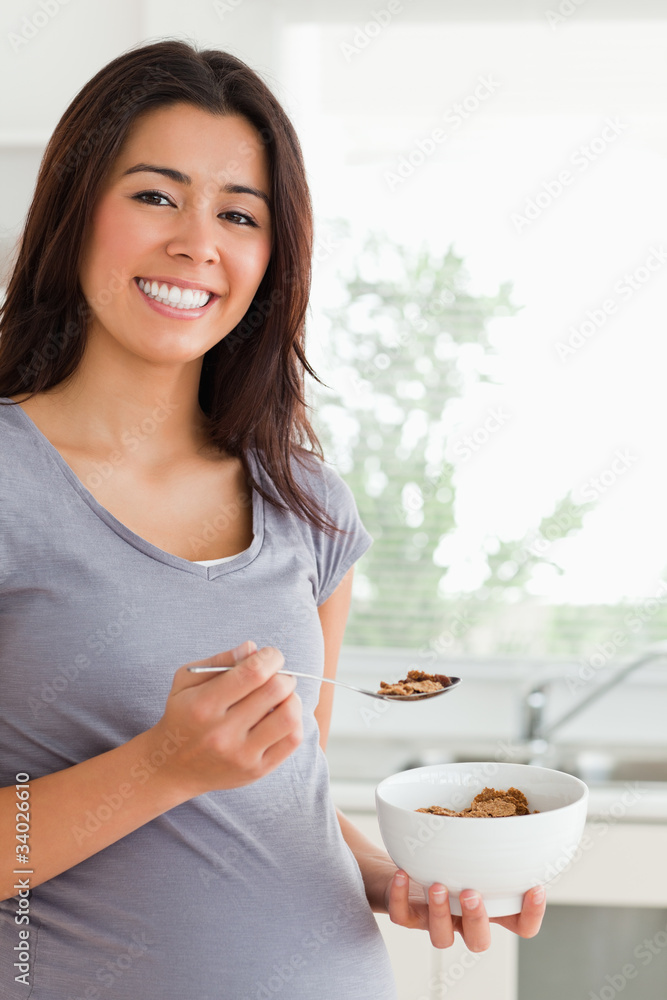 Gorgeous pregnant woman enjoying a bowl of cereals while standin Gorgeous pregnant woman enjoying a bowl of cereals while standin