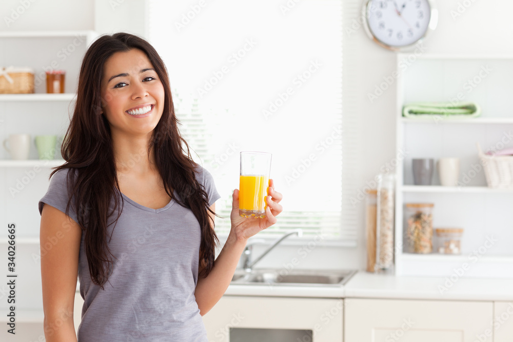 Attractive woman holding a glass of orange juice while standing Attractive woman holding a glass of orange juice while standing