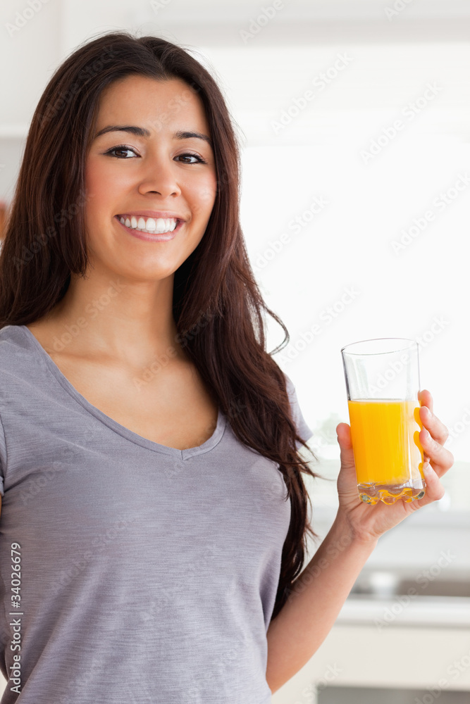 Beautiful woman holding a glass of orange juice while standing Beautiful woman holding a glass of orange juice while standing