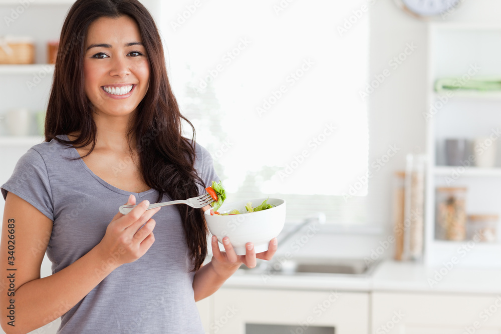 Beautiful woman enjoying a bowl of salad while standing Beautiful woman enjoying a bowl of salad while standing