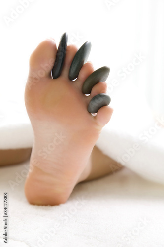 ホットストーンを足の指に挟んだ女性の足元