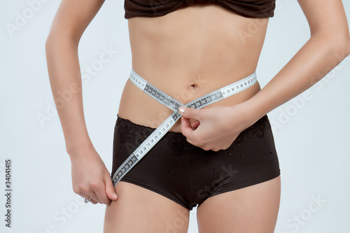 Bild auf Leinwand femme mesurant son ventre plat en boxer marron