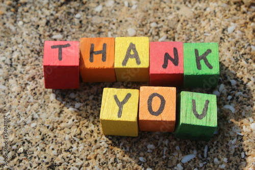 Thank you written with wood cubes, at a rocky beach photo