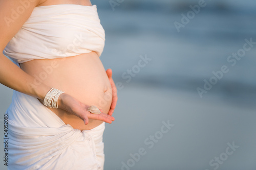 Pregnant woman is holdin shell on her belly photo