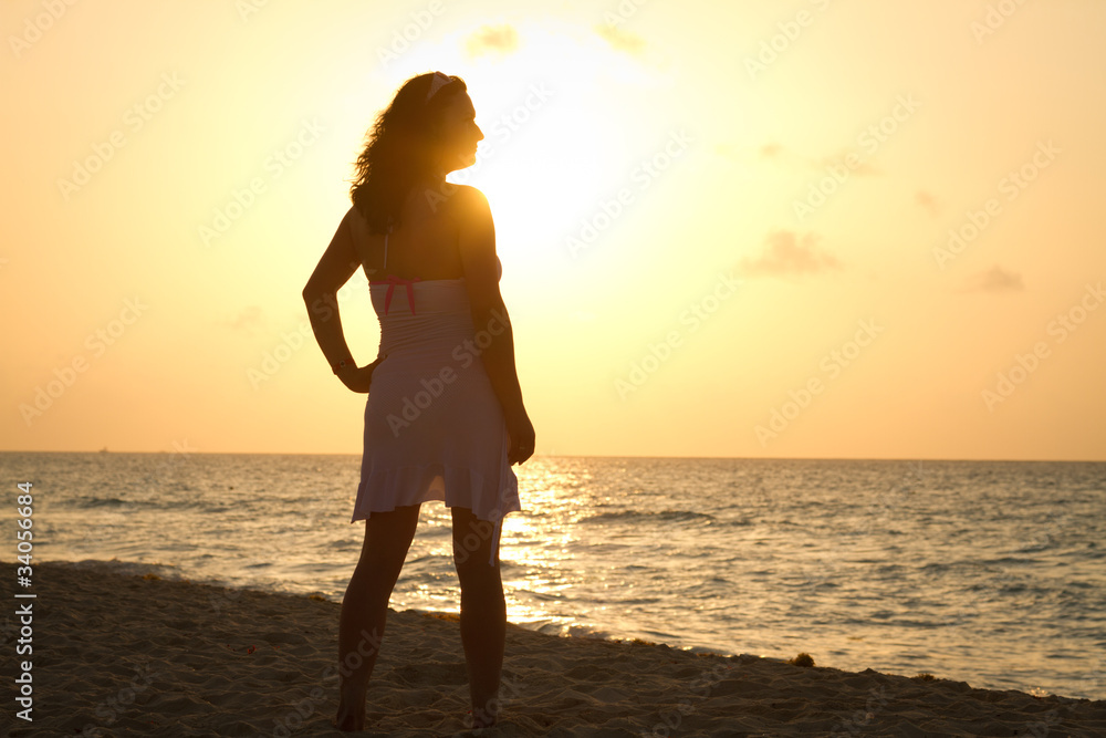 Silhouette of beautiful woman on the beach at sunrise