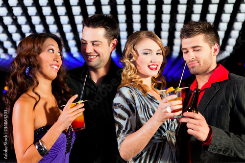 Group of party people with cocktails in a bar or club having fun
