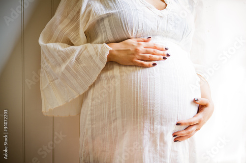 Φωτογραφία pregnant woman in white on white wall