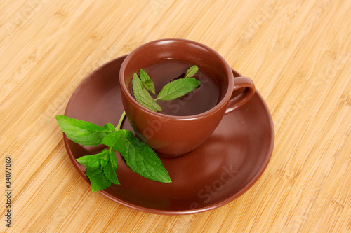 Cup of green tea on the saucer with mint on wooden surface photo