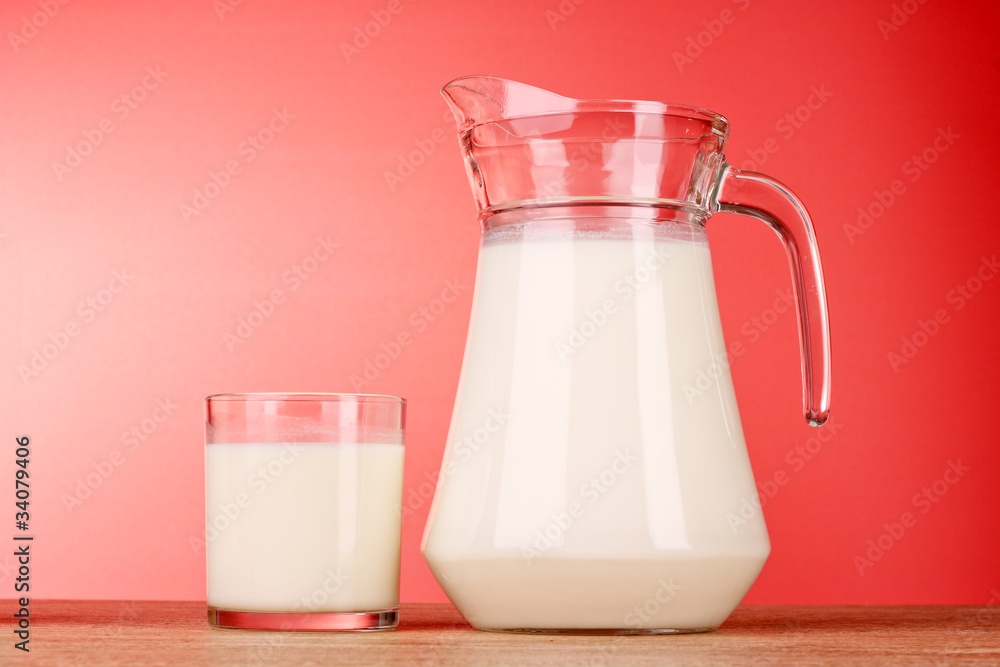 Pitcher and Glass with milk on red background Pitcher and Glass with milk on red background