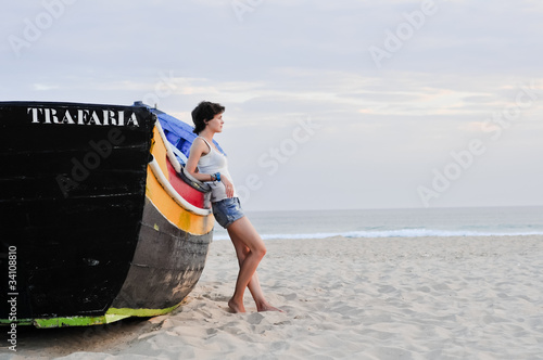 Young girl and a boat on the beach photo