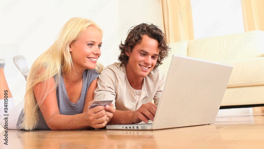 Couple lying on the floor with a laptop Couple lying on the floor with a laptop