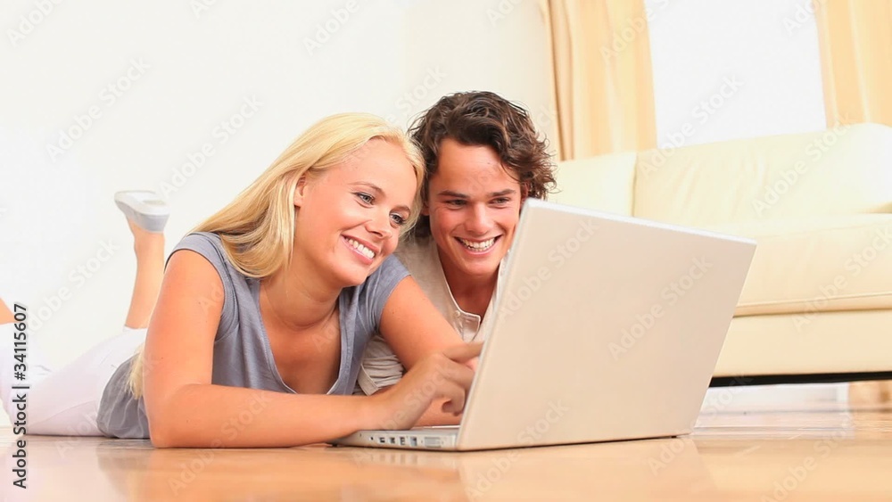 Cute couple lying on the floor with a laptop Cute couple lying on the floor with a laptop