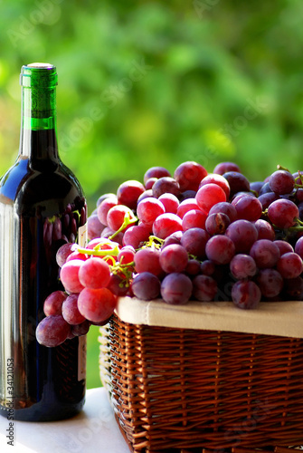 bottle of red wine and grapes in basket