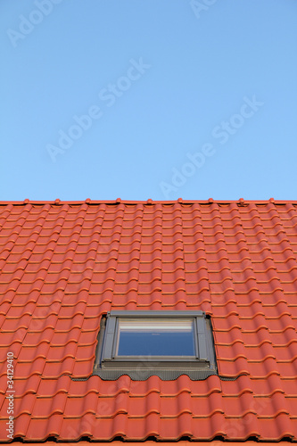 Red roof with one vertical windows and blue sky