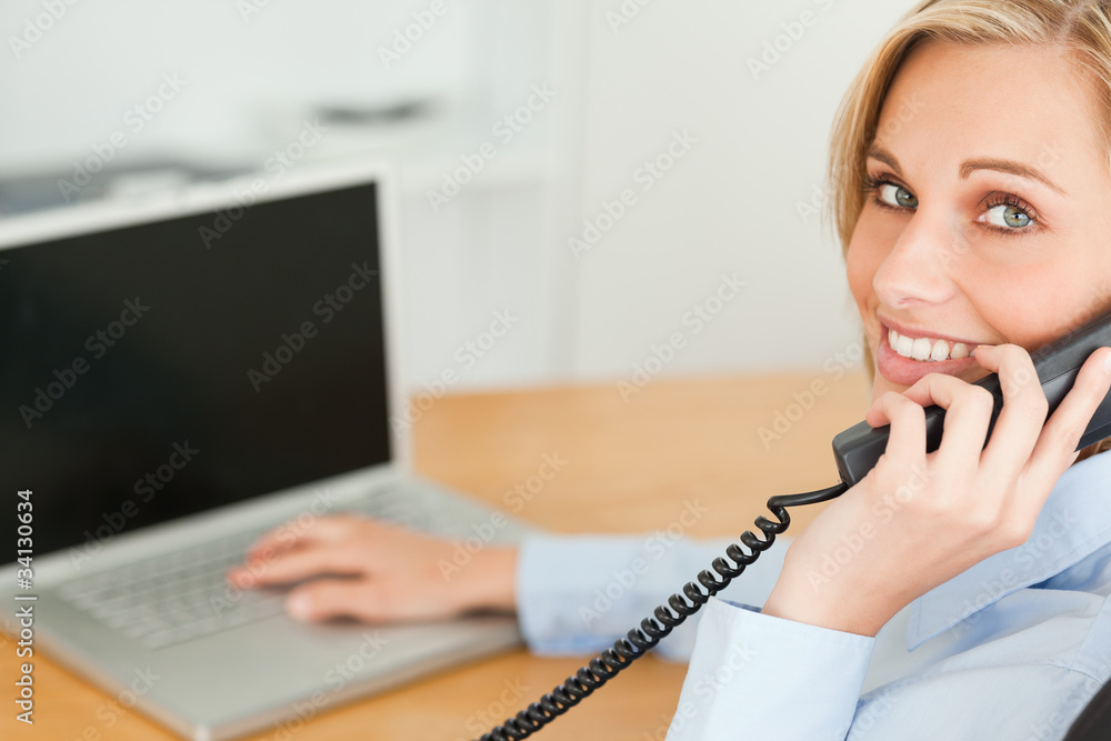 Young businesswoman smiling into camera while on the phone Young businesswoman smiling into camera while on the phone