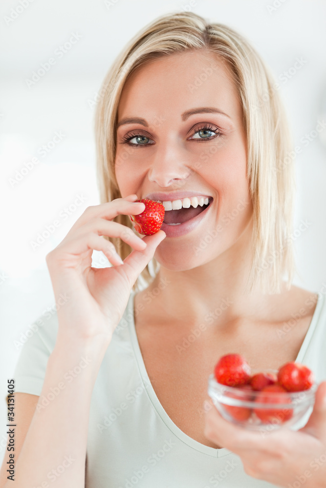 Portrait of a woman enjoying eating strawberries looking into th