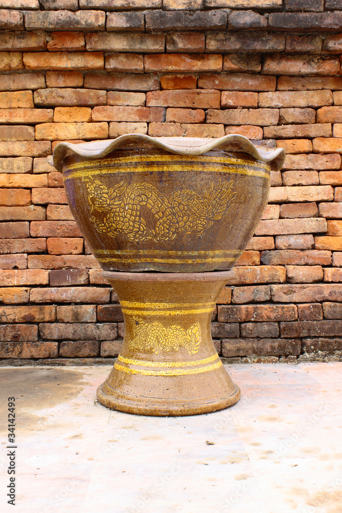 Thai style planter in front of brick wall Thai style planter in front of brick wall