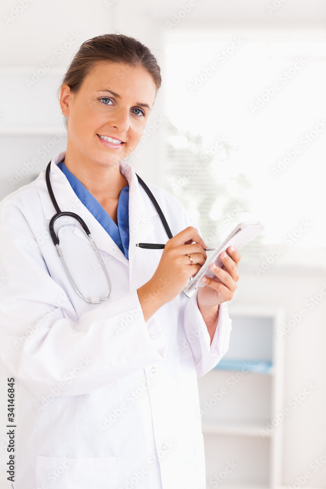 Portrait of a smiling doctor writing something down looking into Portrait of a smiling doctor writing something down looking into