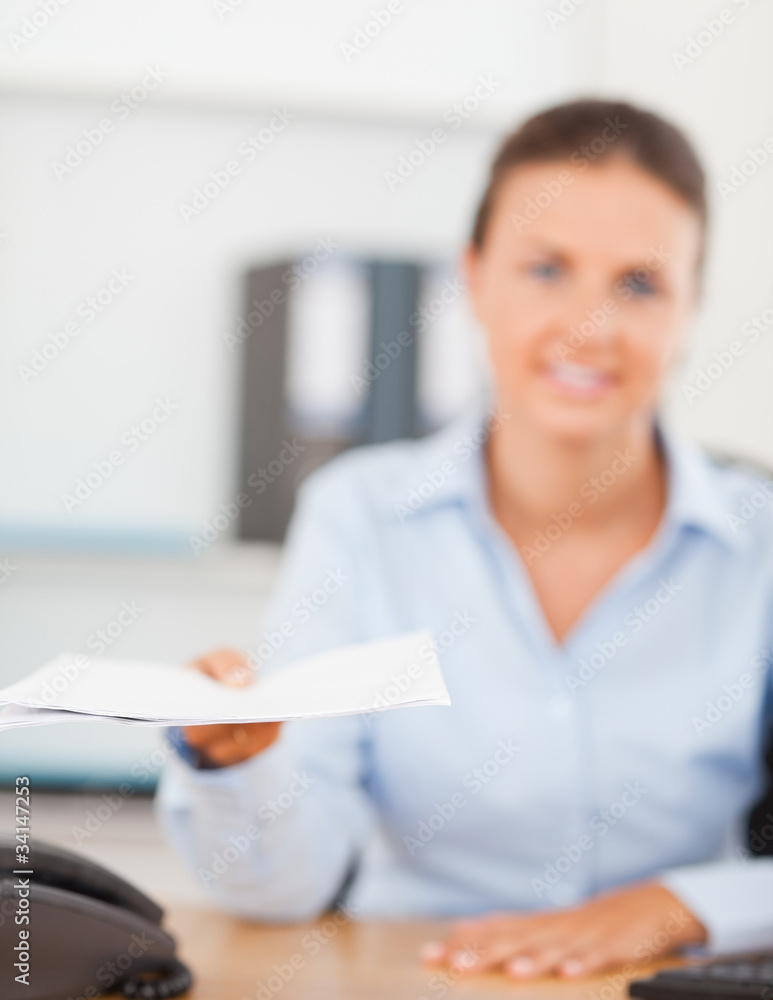 Smiling brunette businesswoman handing out a paper Smiling brunette businesswoman handing out a paper