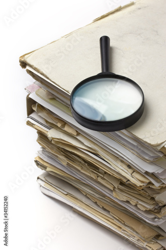 Magnifying lens  on the stack of old paper files