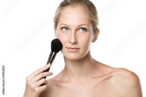 Young female applying mineral powder with make-up brush